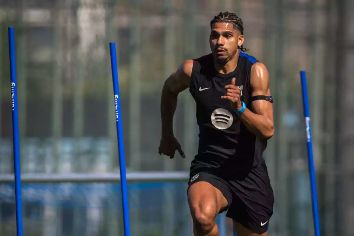 A player training with blue poles on a sports field.